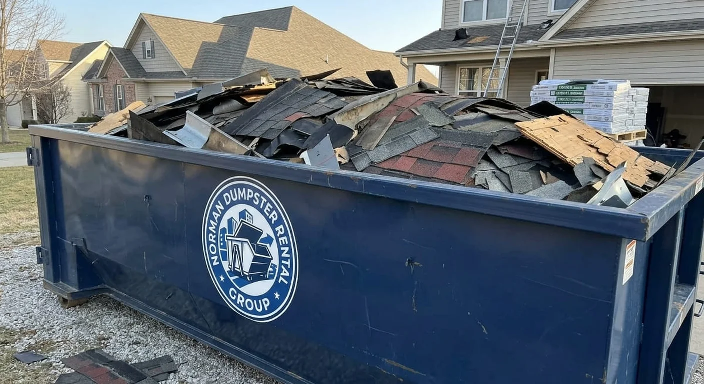 A Norman Dumpster Rental Group dumpster filled with real roofing tear-off debris in front of a home